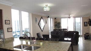 A spacious kitchen with granite countertops, a double sink, and a dining area with a large window offering a city view. - Completely Remodeled Corner Unit With Amazing Gulf Views! (Destin)