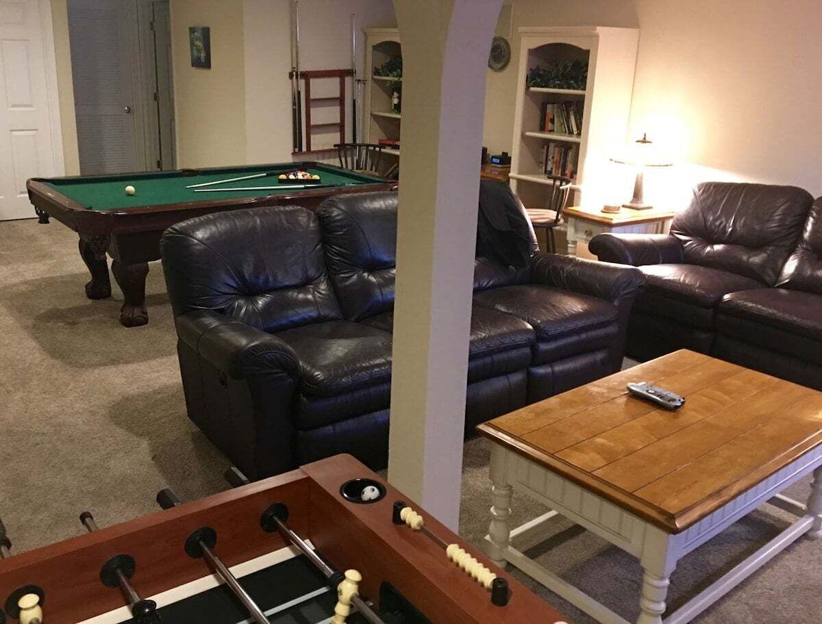 Una sala de estar con mesa de billar, sofás de cuero, mesa de futbolín y una mesa de centro.