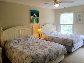 A bedroom with two beds, a ceiling fan, a window with blinds, and a painting on the wall. - Bear Trap Dunes * 4BR Luxury Resort home (Ocean View)
