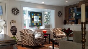 A living room with patterned armchairs, a coffee table, a rug, and a decorative window with stained glass. - Great South End / Back Bay location, 1 bed condo near T station  (Boston)