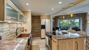Una cocina moderna con salpicadero de piedra, armarios de madera y una isla integrada con asientos.
