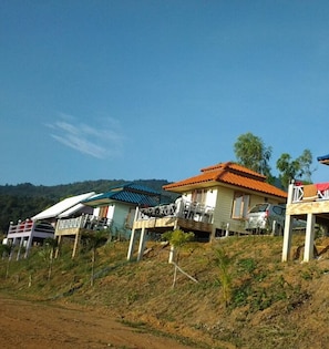 Una hilera de casas con diferentes colores y diseños de tejados, ubicadas en una ladera con cielo despejado.