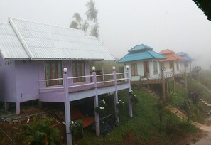 A row of houses with a flat roof and a balcony, surrounded by greenery. - Ban Sukjai Resort (Khao Kho)