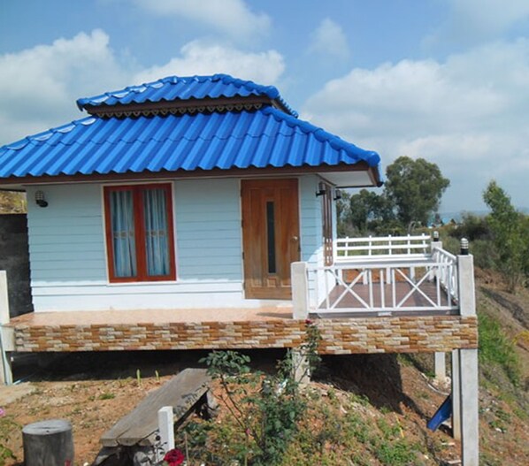 A single-story house with a blue roof, a wooden door, and a white porch.