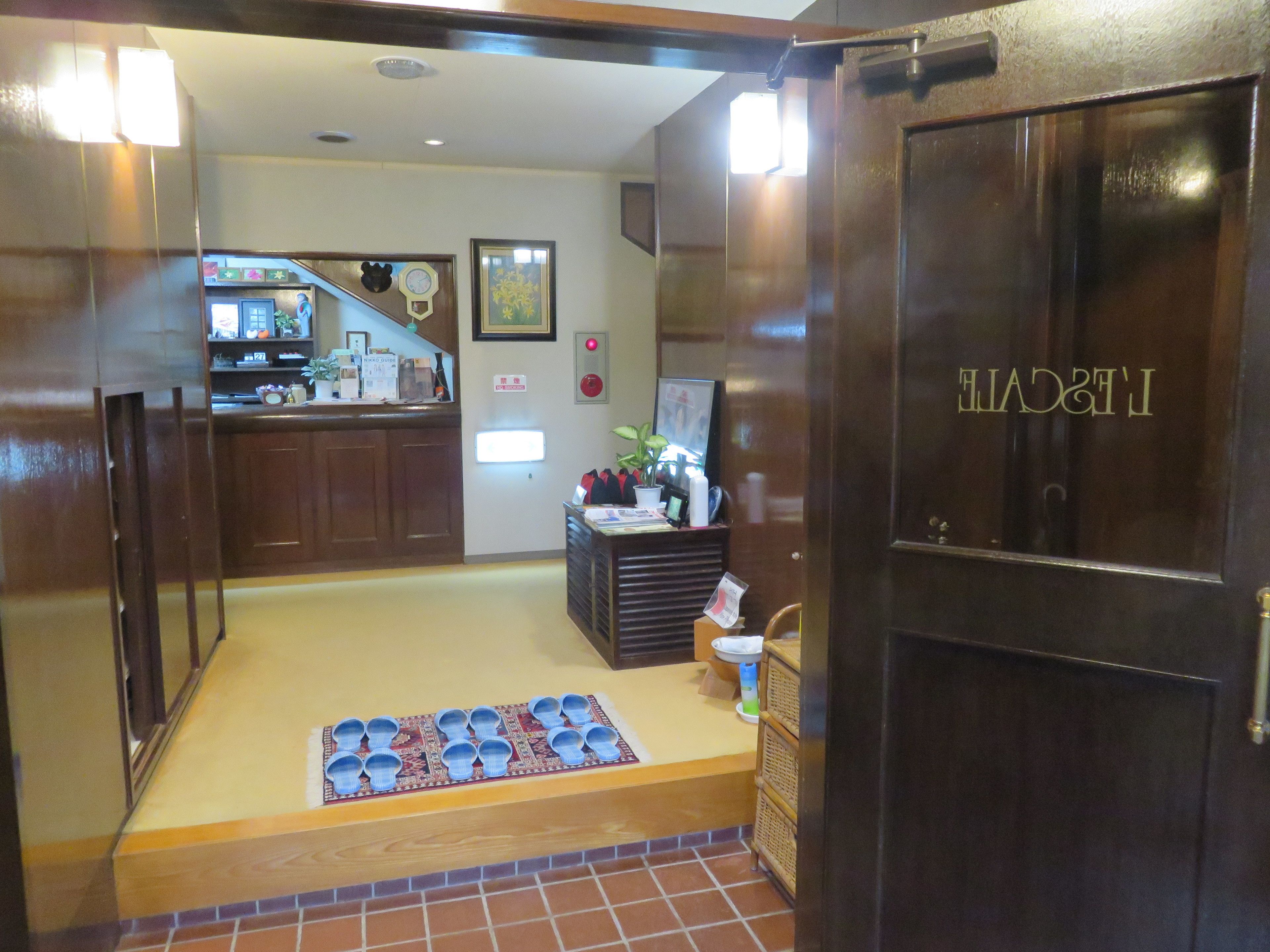 Un vestíbulo de hotel con una recepción, un rincón de descanso y una puerta de madera que dice 'RESORT'.