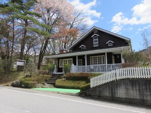 A two-story house with a porch, a small staircase, and a white picket fence. - Japan Nikko Pension L'escale (Nikko)
