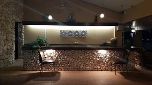 Een bar met een stenen muur, twee stoelen en een hanglamp.