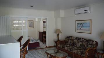 A living room with a sofa, a coffee table, a chair, a lamp, a picture frame, and an air conditioning unit.
