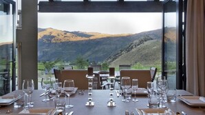 Une table à manger dressée pour six personnes, avec une vue imprenable sur les montagnes grâce à de grandes fenêtres.