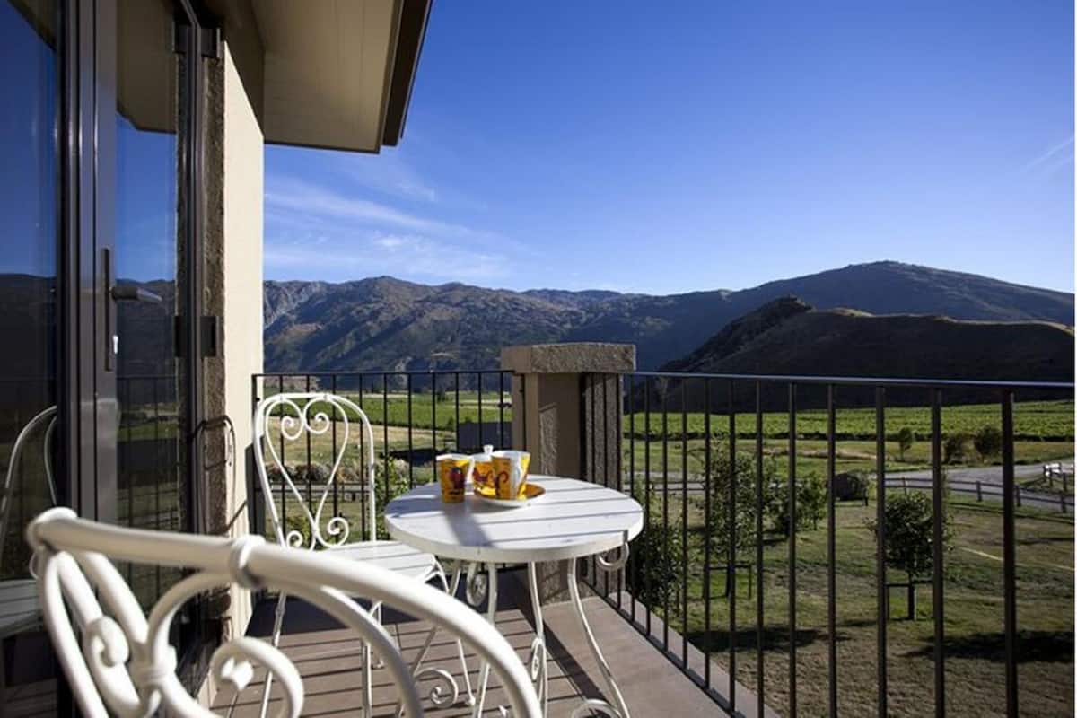 Uma varanda com mesa e cadeiras, com vista para uma paisagem montanhosa.