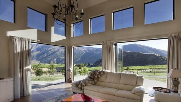 Un salon spacieux avec un canapé, une table basse et une vue sur les montagnes grâce à de grandes fenêtres.