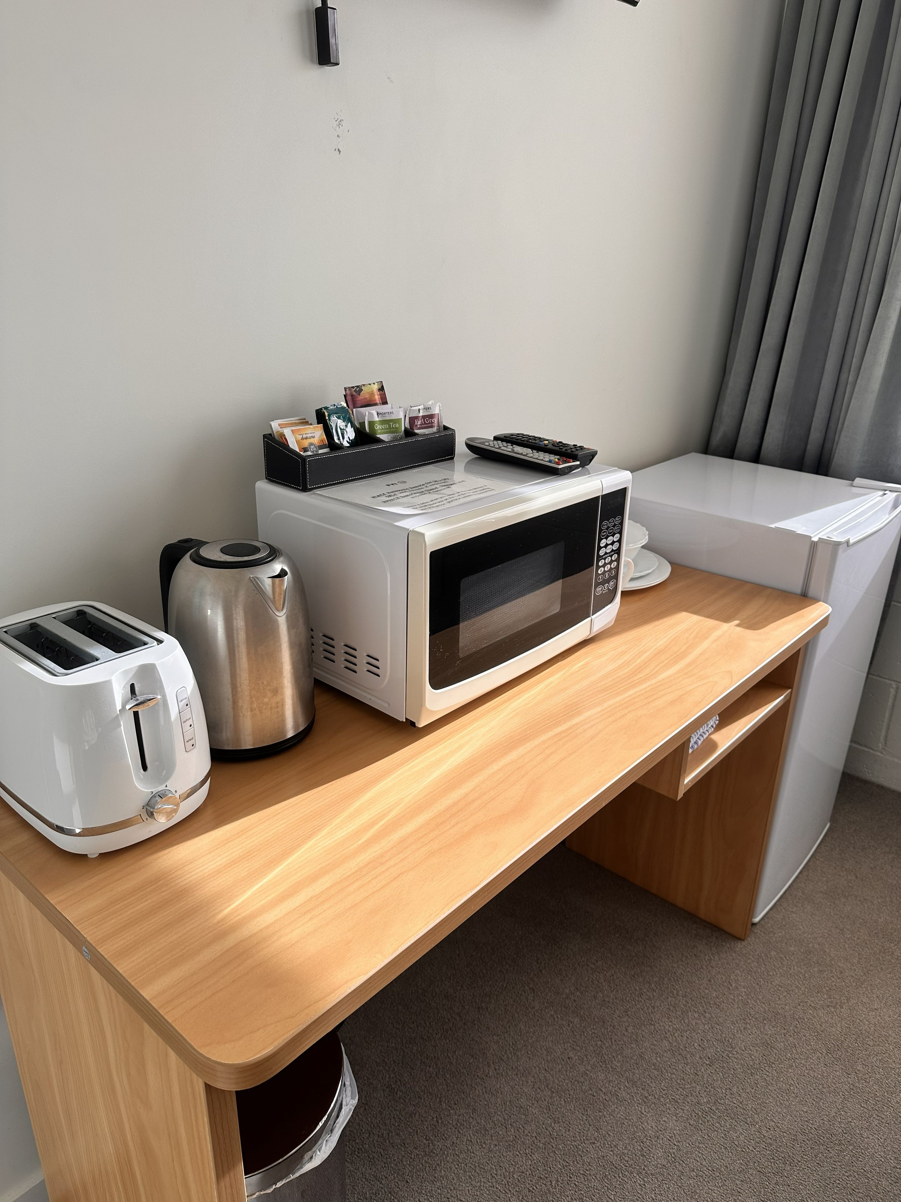 A kitchenette with a microwave, toaster, and coffee maker on a wooden countertop.