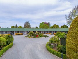 A motel with a green roof, a central parking area, and well-maintained landscaping.