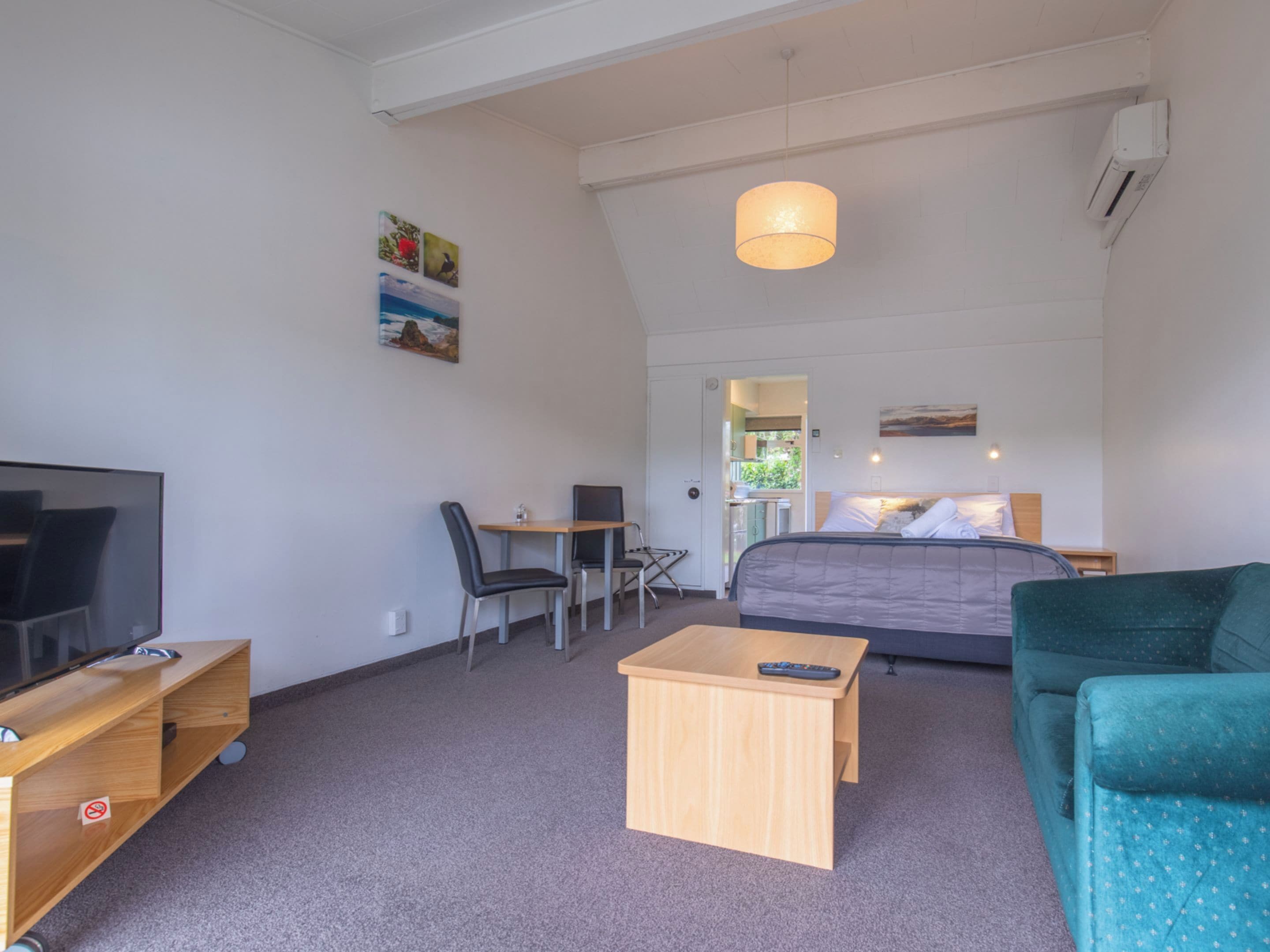 Una habitación de hotel moderna con una cama, un escritorio, una silla, un televisor y un sofá.
