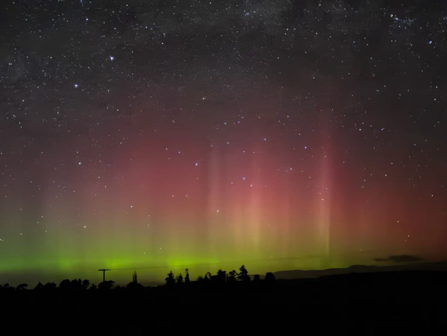 A night sky with stars and a green aurora.