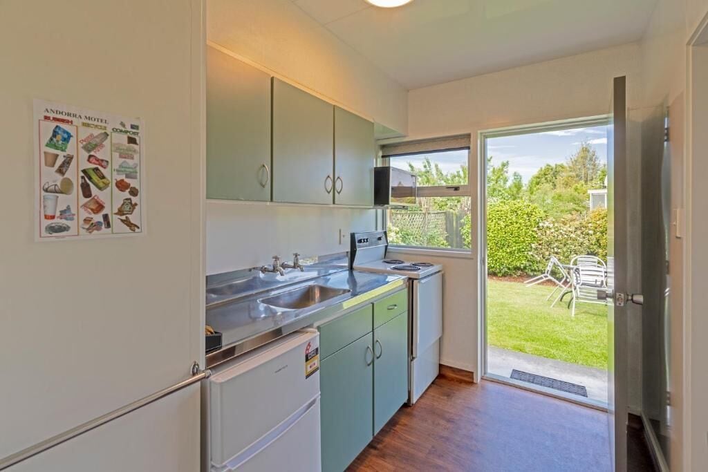 A compact kitchen with a sink, cabinets, and a window leading to a patio.