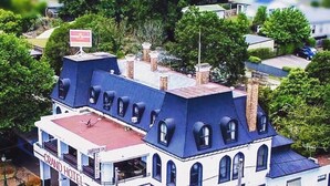 Un edificio de dos pisos con un llamativo letrero que dice “GRAND HOTEL”, varias chimeneas y un techo rojo.