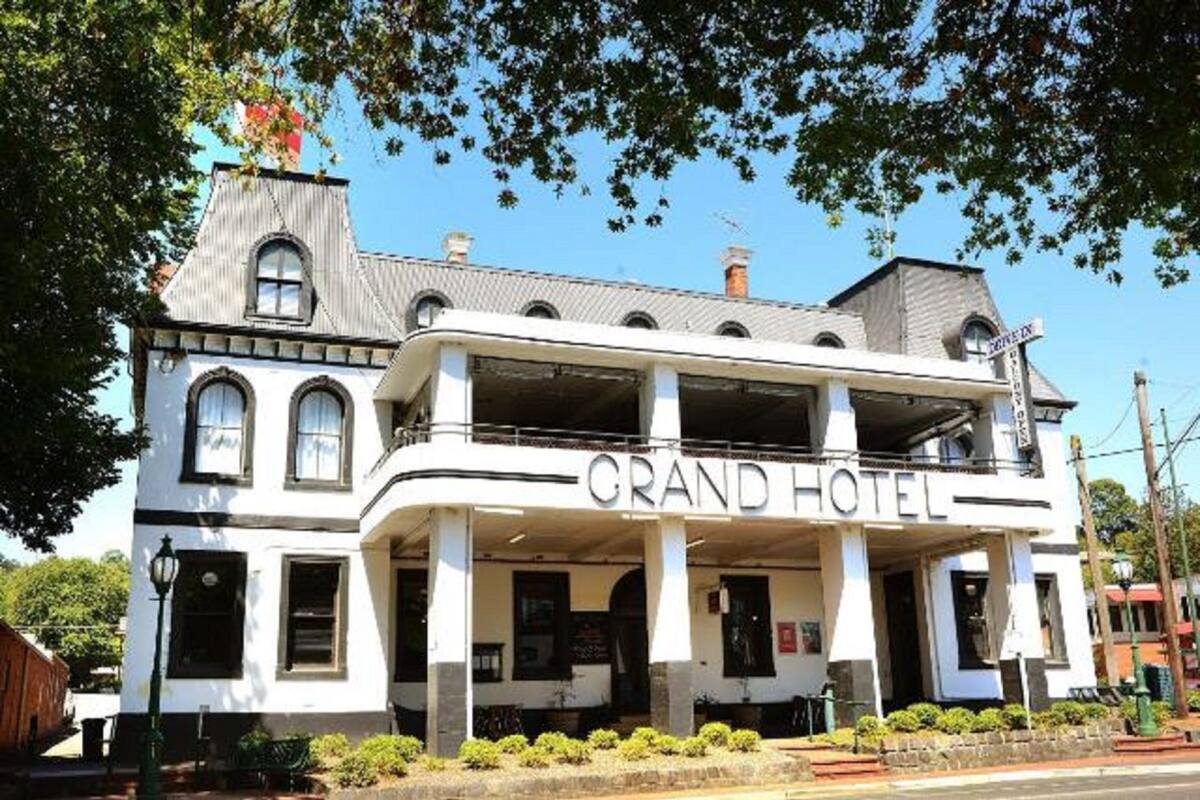 Un immeuble de deux étages, avec une enseigne indiquant « GRAND HÔTEL » sur la façade.