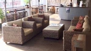 Un amplio salón con mobiliario de mimbre, una mesa baja en el centro y una barra.