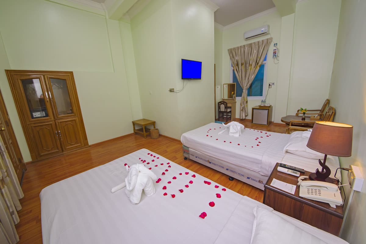 Une chambre d’hôtel avec deux lits, une télévision, un bureau avec une lampe et un téléphone.