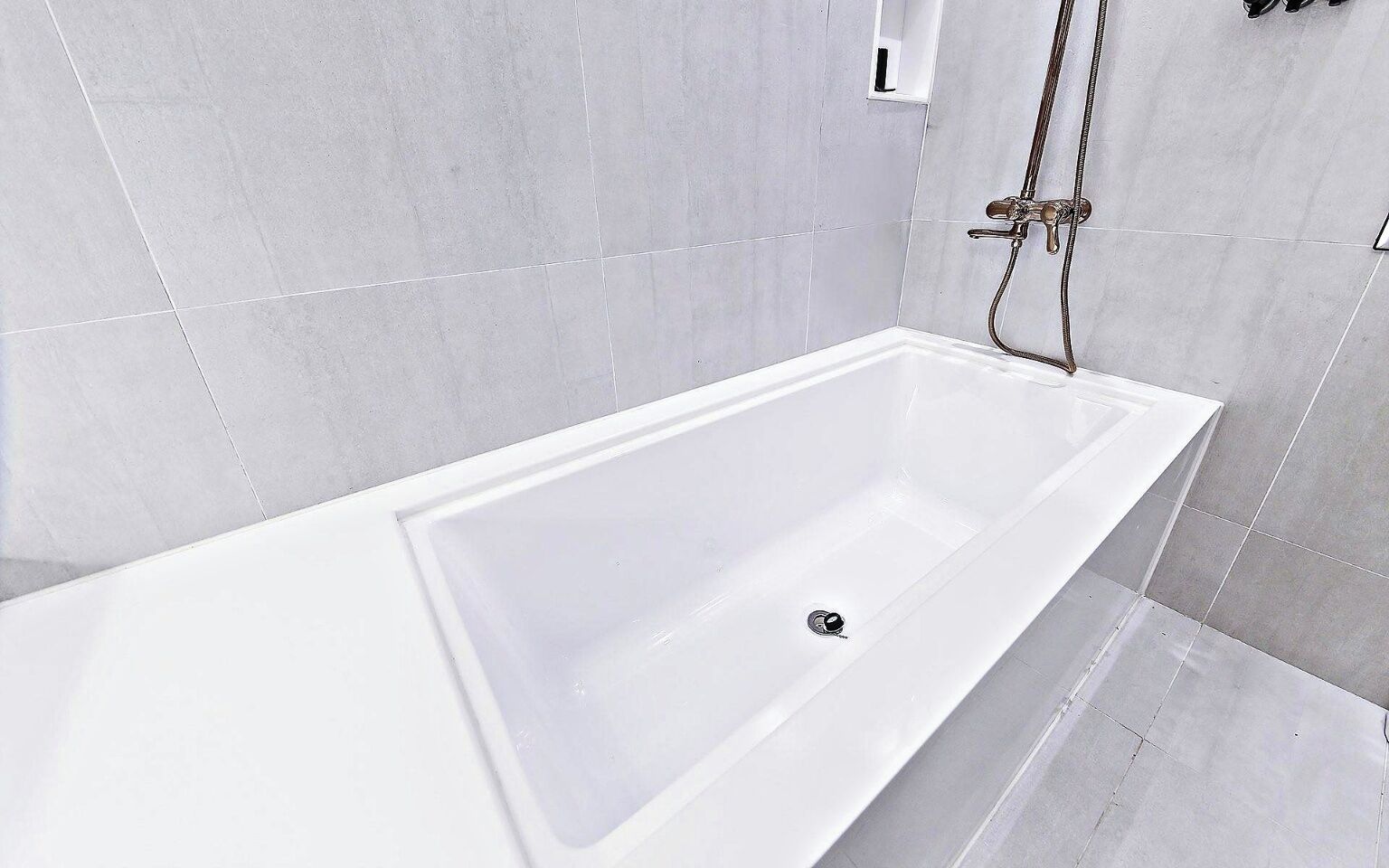 A modern bathroom with a white bathtub, a shower area, and tiled walls.