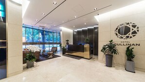 A modern hotel lobby with a reception desk, potted plants, and a large window with a view of trees. - Hotel Cullinan (Seoul)