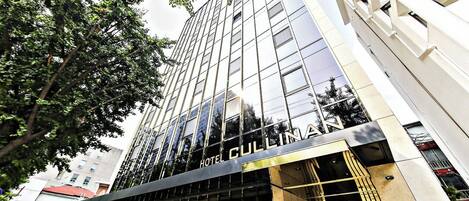 Un moderno edificio de hotel con fachada de vidrio reflectante y el nombre "HOTEL CULLMAN" claramente visible.