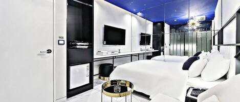 Habitación de hotel moderna con una cama grande, un escritorio, un televisor y un baño.