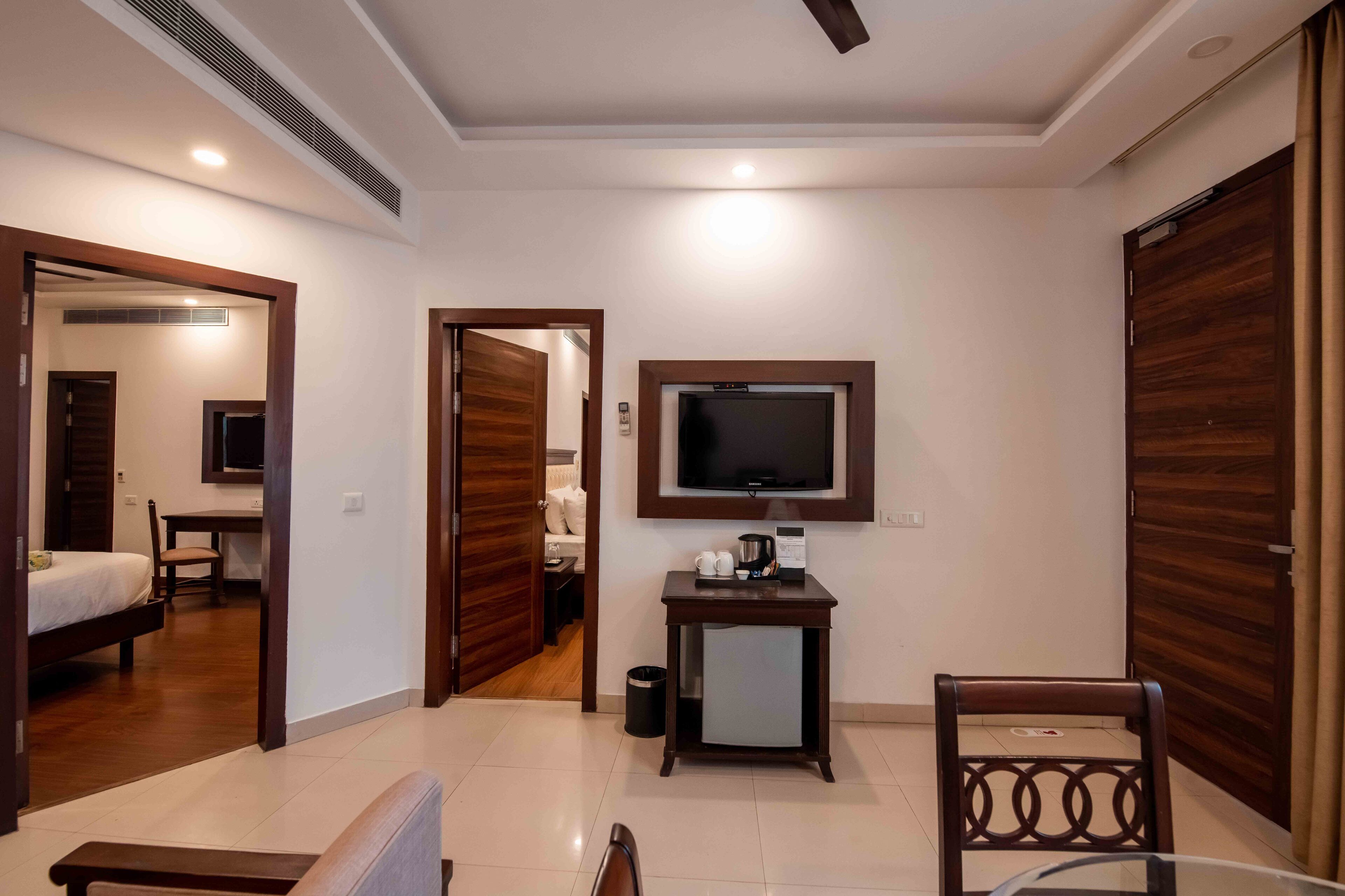 Una habitación de hotel con cama, escritorio, televisor montado en la pared y armario.