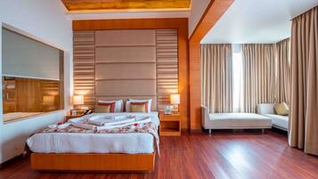 A modern hotel room with a large bed, bedside tables, a sofa, and a large window with curtains.