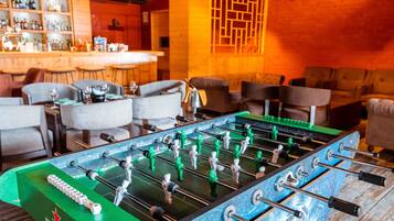 A foosball table in a bar area with a bar counter and seating.