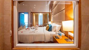 Une chambre d’hôtel avec un grand lit, une table de chevet avec une lampe et une vue sur l’extérieur.