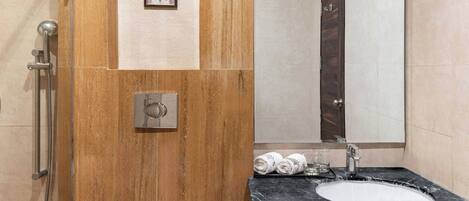 Een badkamer met een houten wastafelmeubel, een wastafel, een douche en een spiegel.
