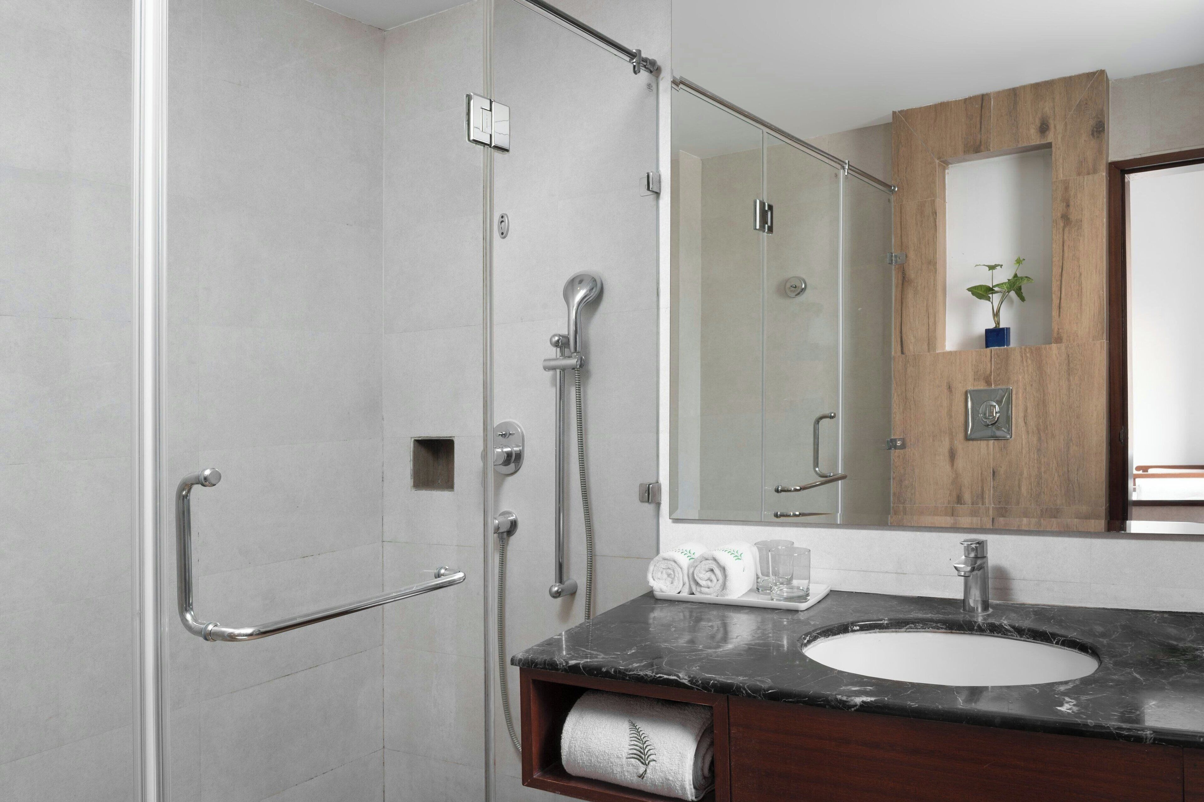 A modern bathroom with a glass shower enclosure, a marble sink, and a wooden vanity.
