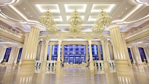 A grand lobby with high ceilings, ornate chandeliers, and large windows.