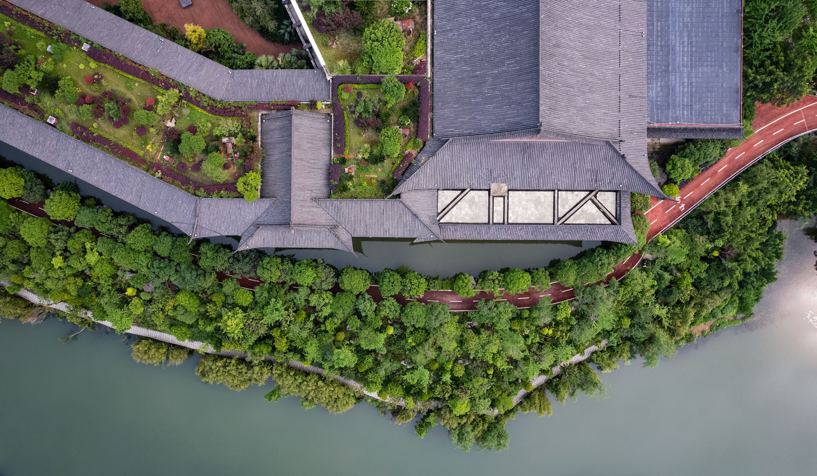Vista aérea de un edificio tradicional con patio, rodeado de abundante vegetación y una masa de agua.