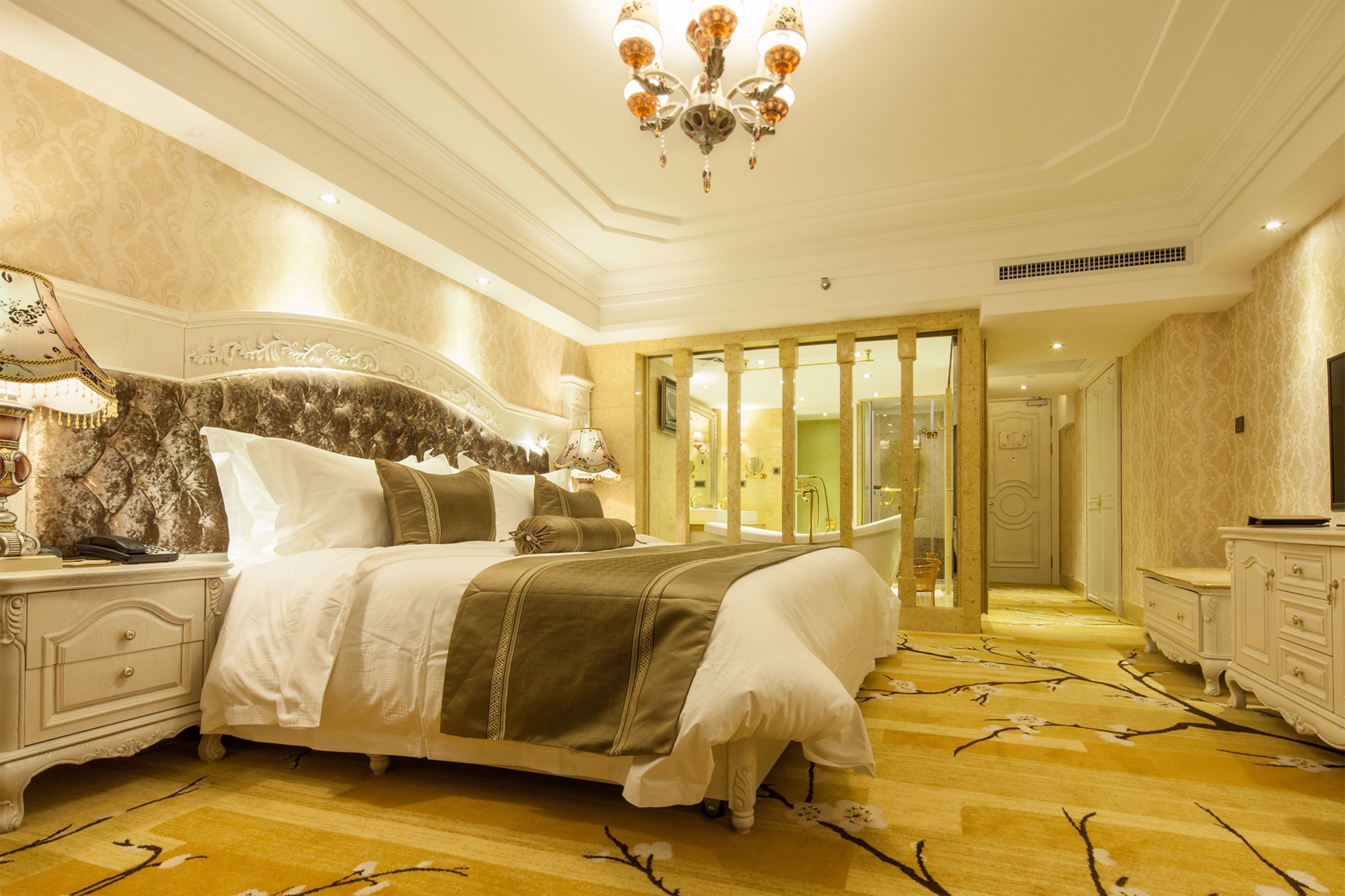 A spacious bedroom with a large bed, a chandelier, and a wooden floor.