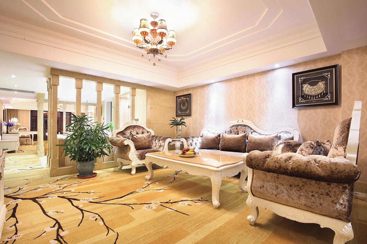 A spacious living room with a large sofa set, a coffee table, and a chandelier.