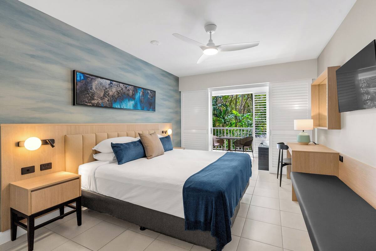 Ein modernes Schlafzimmer mit Bett, Nachttischen, Schreibtisch und Deckenventilator.