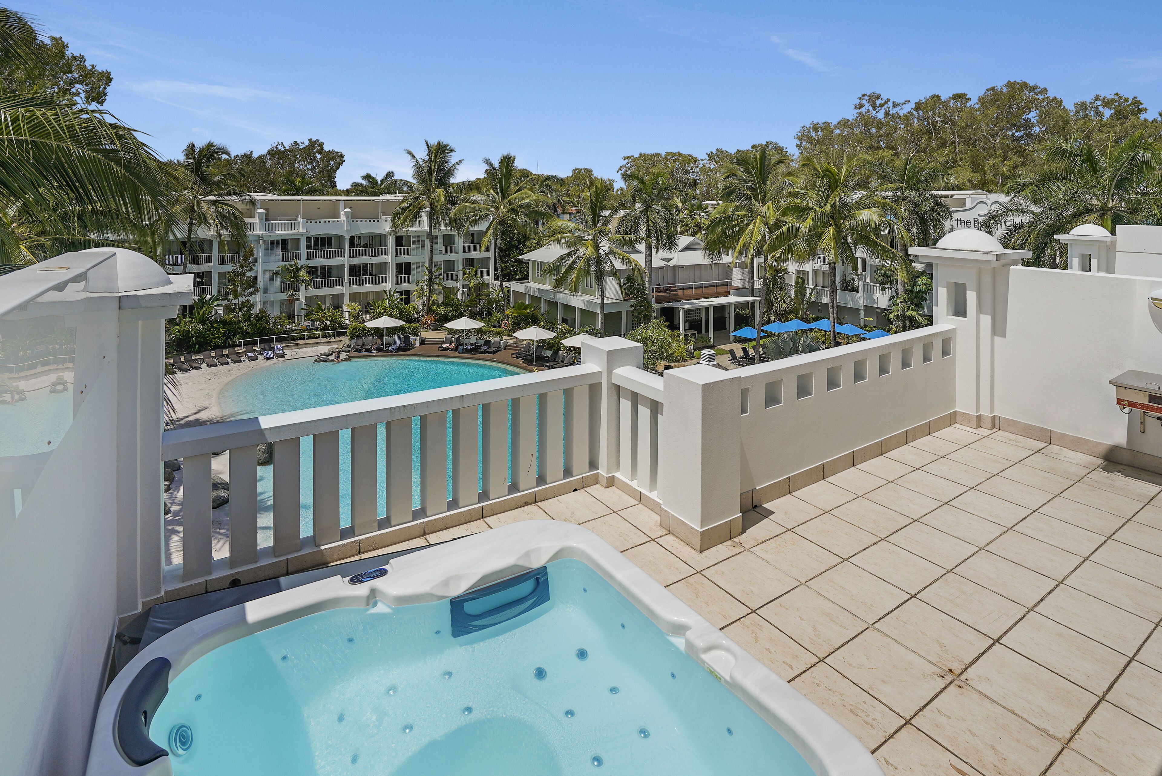 A hotel with a pool, a hot tub, and a view of the surrounding buildings and palm trees.
