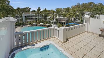 A hotel with a pool, a hot tub, and a view of the surrounding buildings and palm trees.