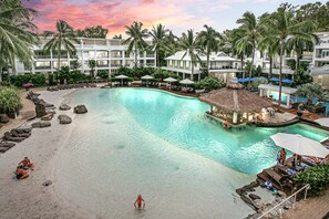 A resort with a large pool, lounge areas, and a beach.