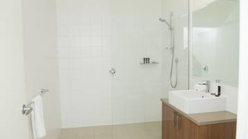 A modern bathroom with a shower, a sink, and a mirror.