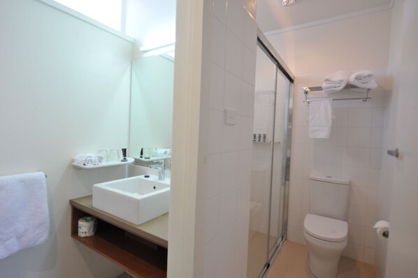 A modern bathroom with a glass-enclosed shower, a white sink, and a toilet. - The Griff Motel (Griffith)