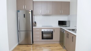 A modern kitchen with stainless steel appliances, wooden cabinets, and a tiled backsplash.