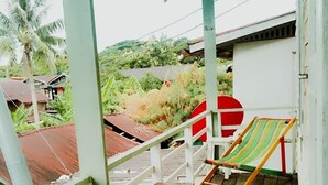 A wooden deck with a bench and a striped lounge chair, overlooking a rural landscape with houses and vegetation. - Baanklangsoi (Prachuap Khiri Khan)