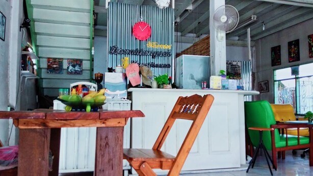 A cafe with a wooden table, chairs, a white counter, and a clock on the wall. - Baanklangsoi (Prachuap Khiri Khan)