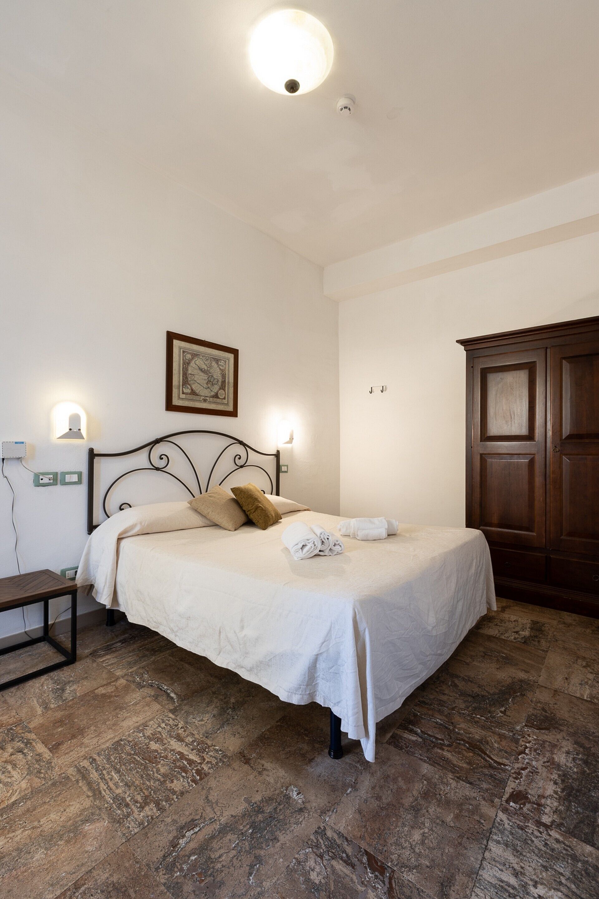 A bedroom with a bed, bedside table, wall-mounted light, and a wardrobe.