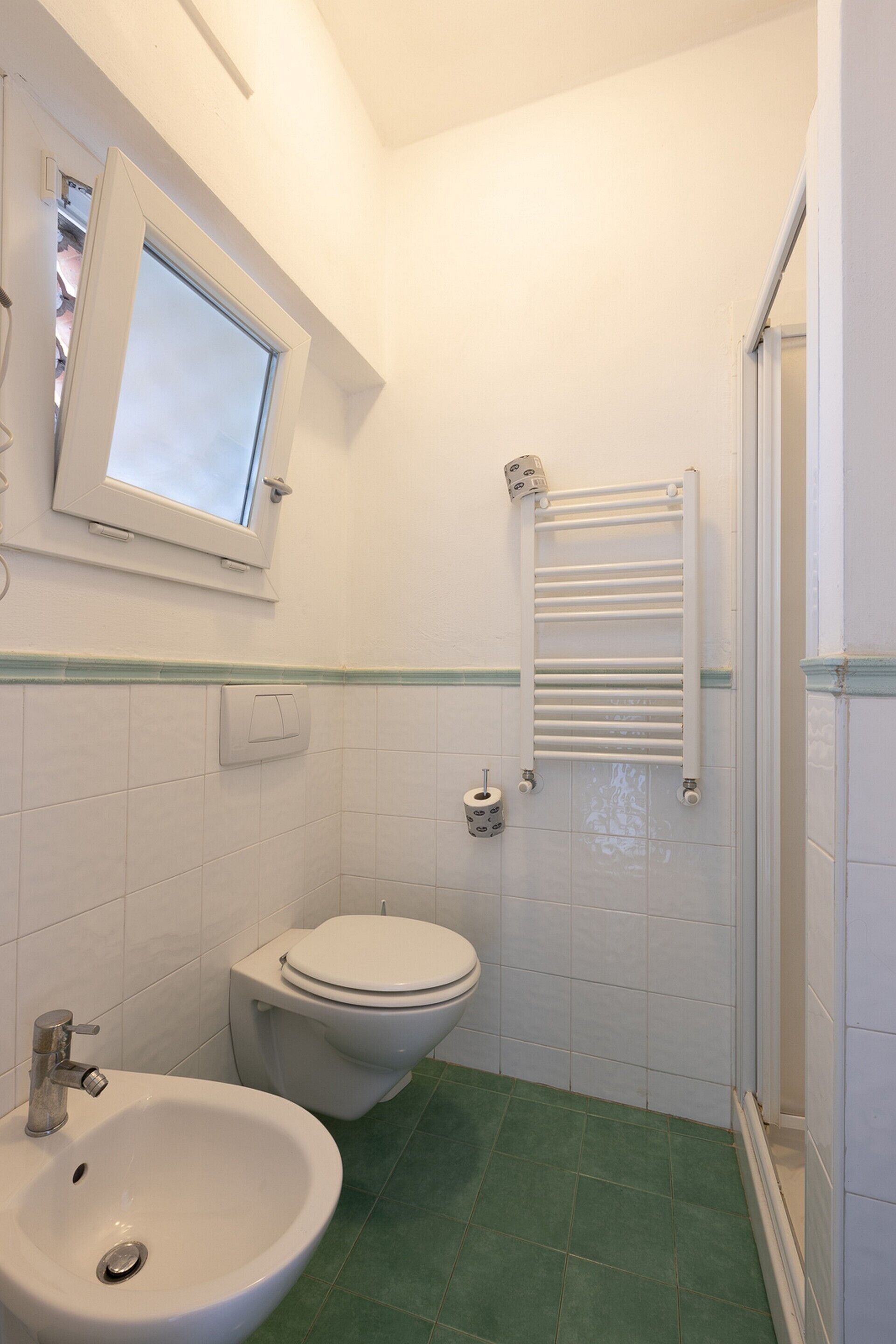 A small bathroom with a toilet, sink, and a towel rack.