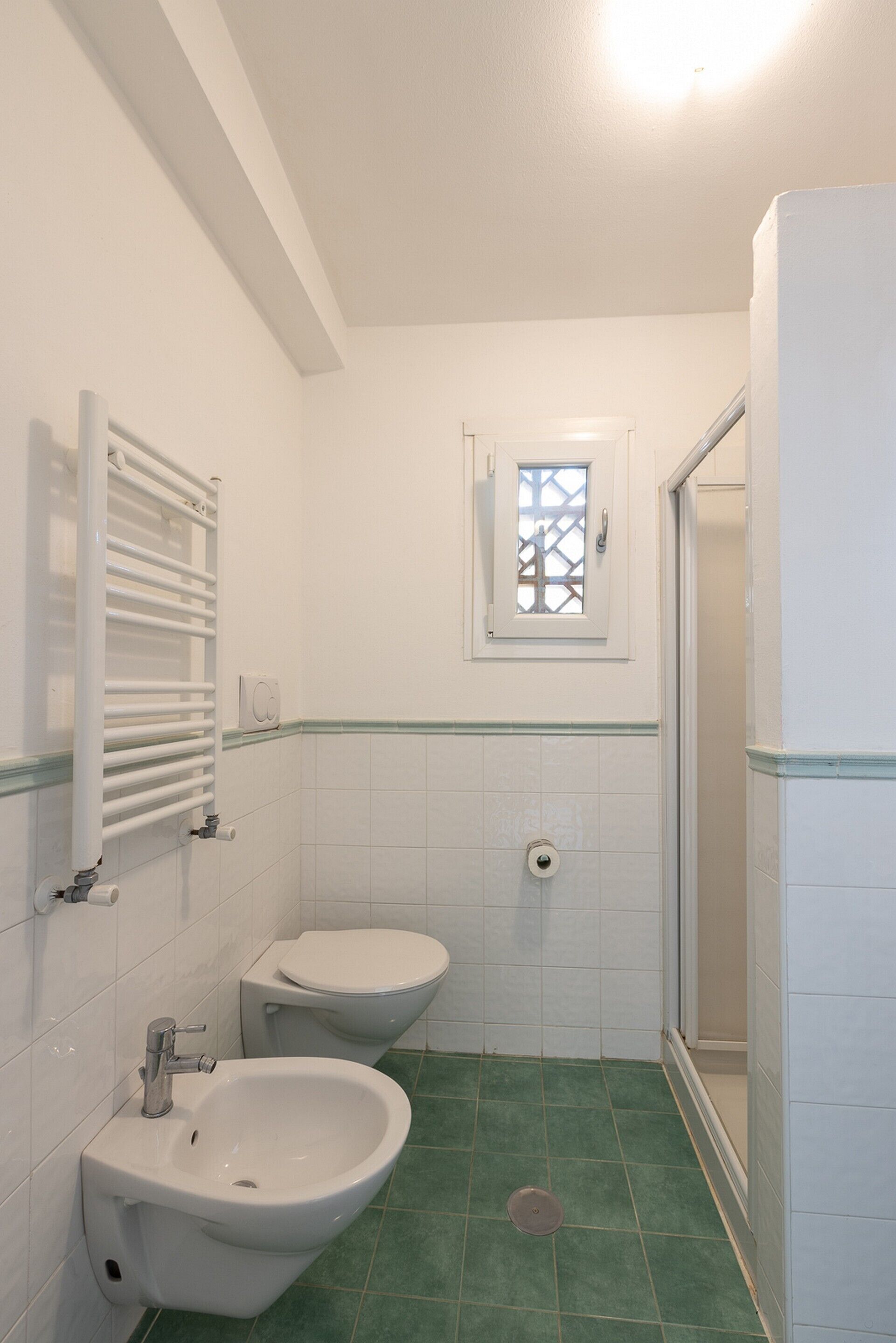 A bathroom with a bidet, toilet, and a window.